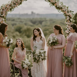 Wedding Party and Bridesmaids with flowers under floral wedding arch